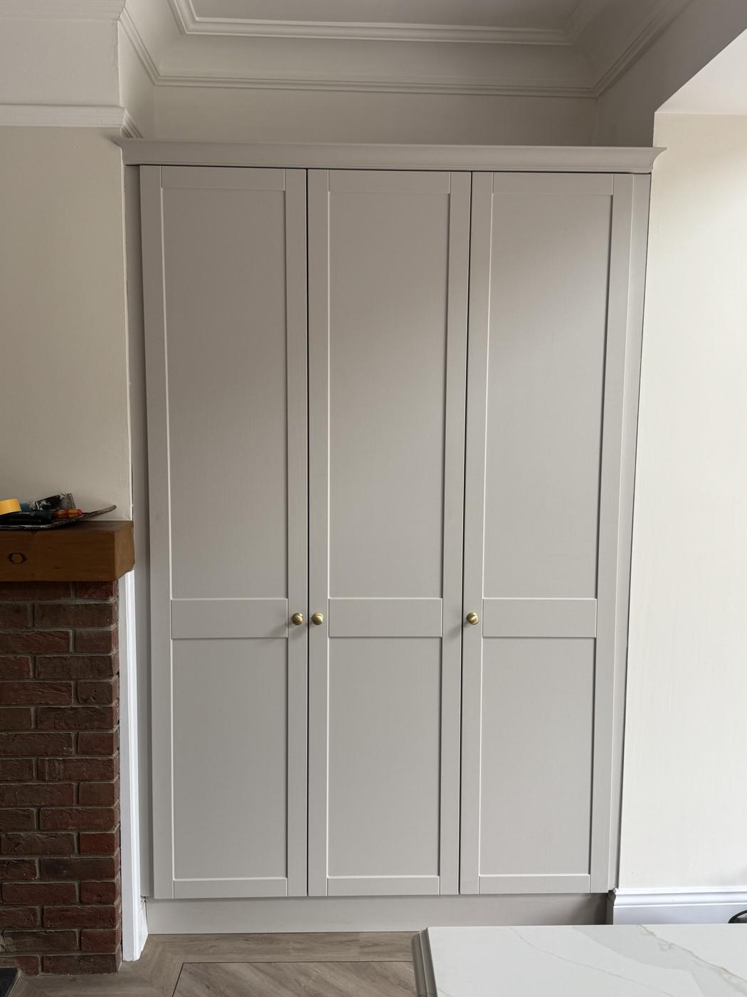 Light grey three-door shaker cupboard fitted to the ceiling