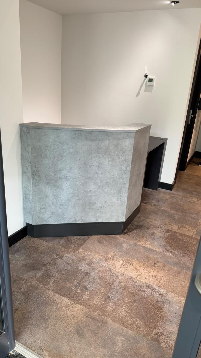 Side view of the concrete-effect reception counter with dark plinth